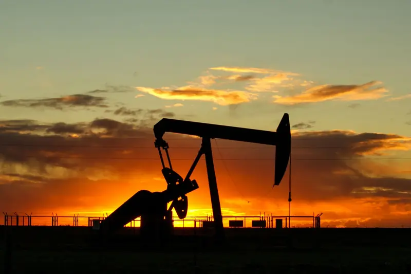 Oil pumpjack silhouetted against a sunset sky